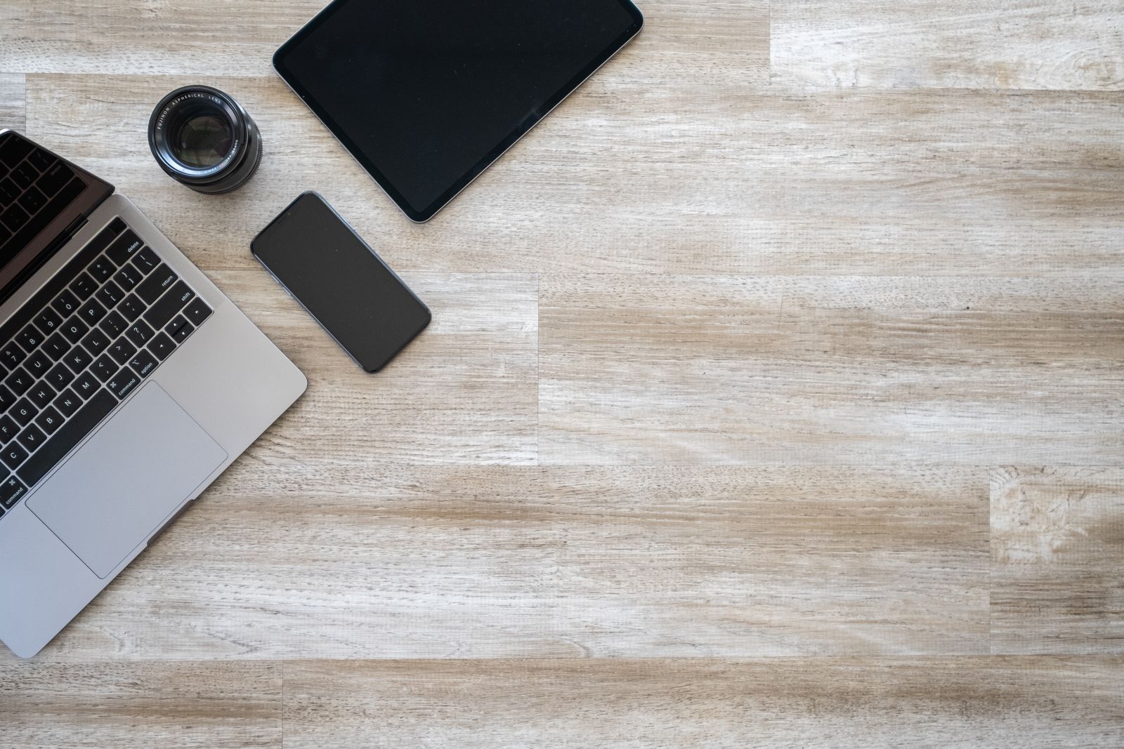 Workspace with a laptop, tablet and phone on a wooden desk