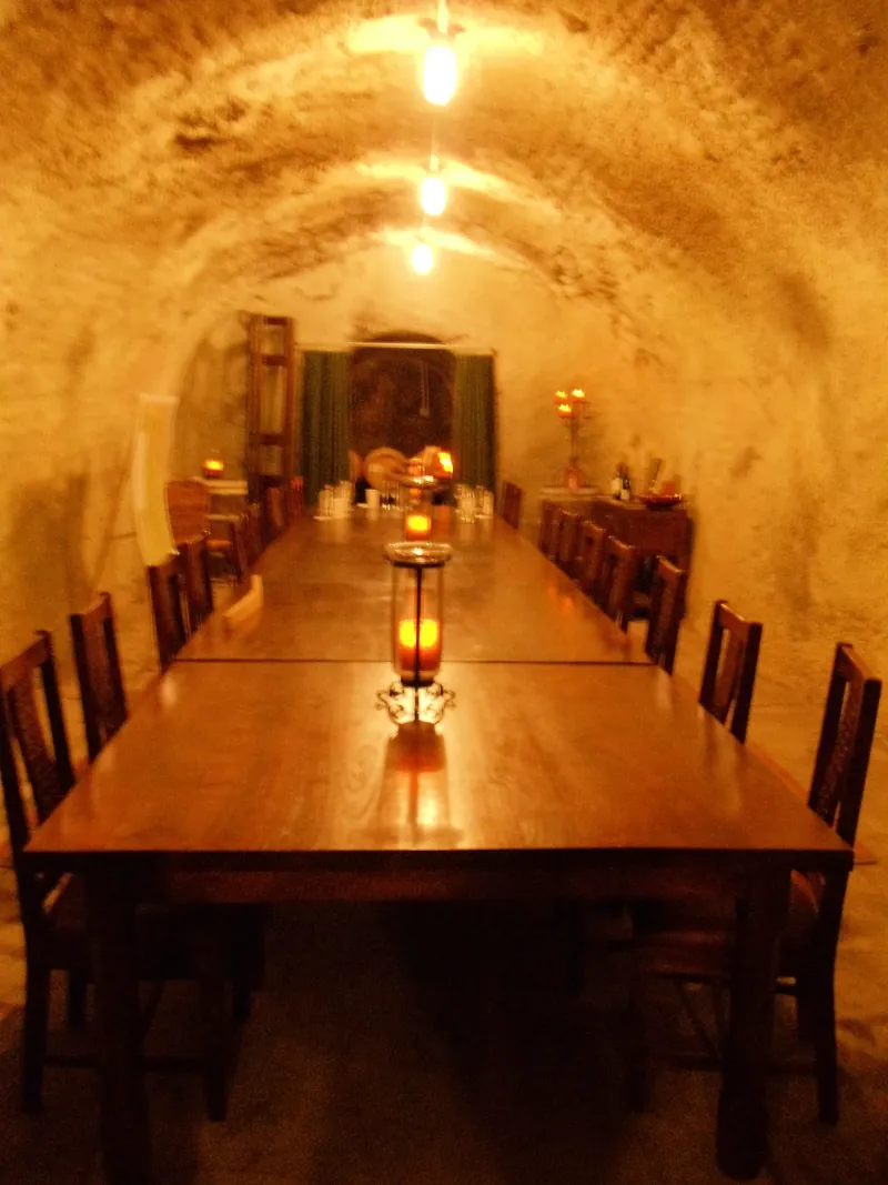 A long candlelit table in a vaulted cellar dining room